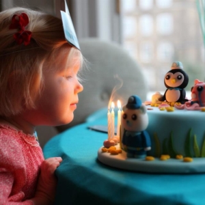 Little girl blowing candles out on Octonauts celebration cake